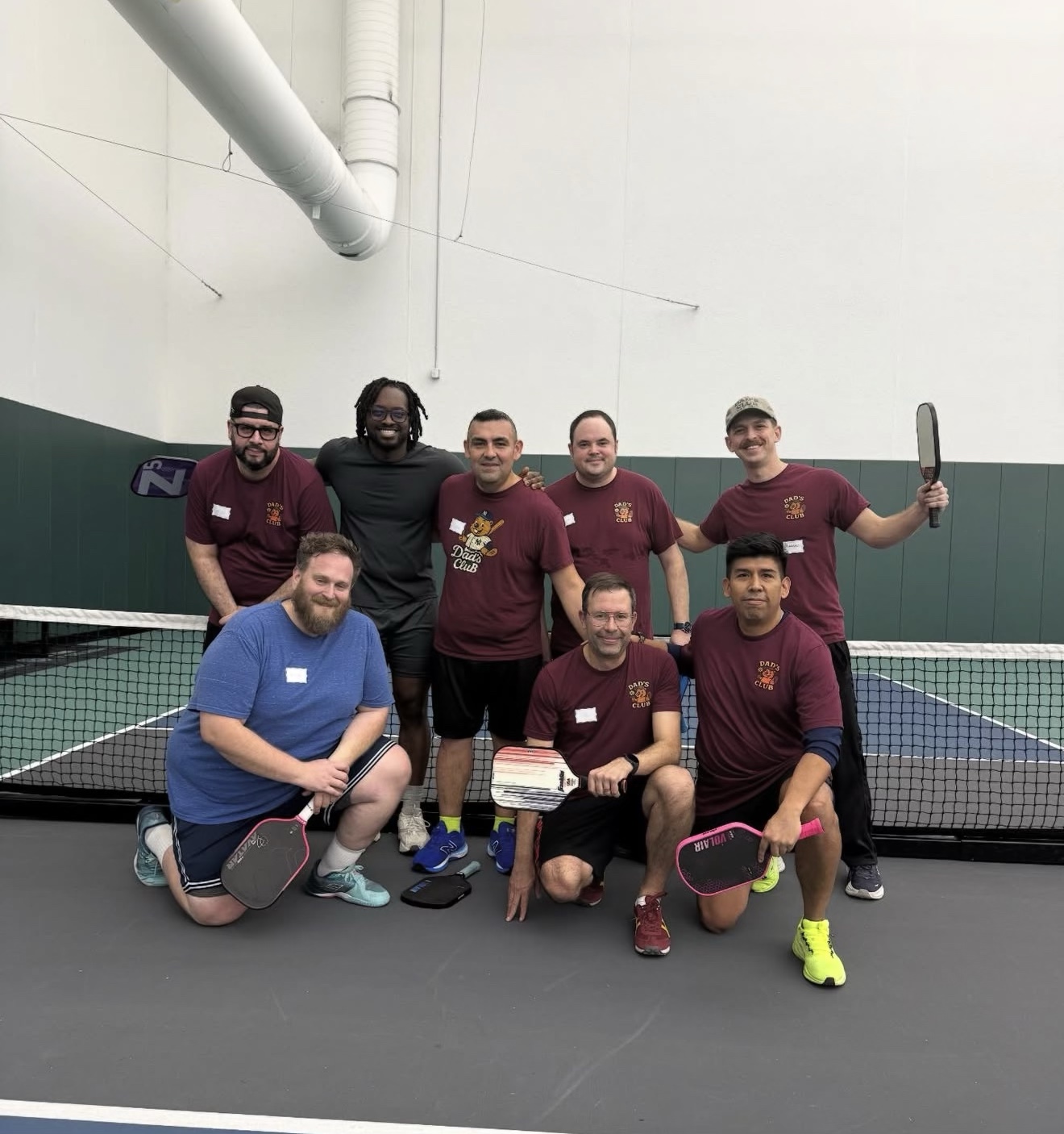 Dads pose together with pickleball paddles