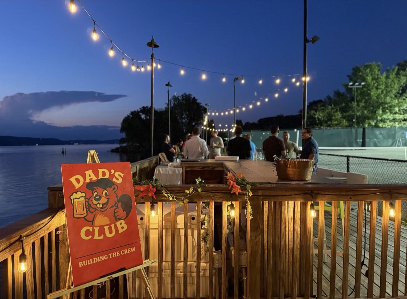 Dad’s Club sign by the waterfront under string lights